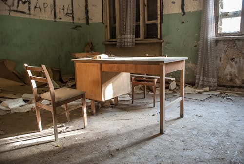 A Wooden Desk and Chair in an Abandoned Building