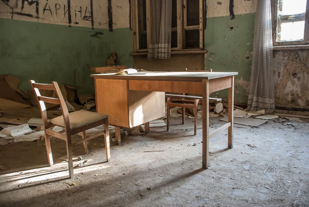 Scrivania e sedia in una stanza rimasta chiusa a lungo, con polvere depositata