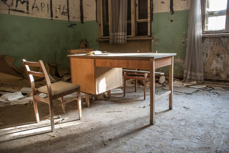 Scrivania e sedia in una stanza rimasta chiusa a lungo, con polvere depositata