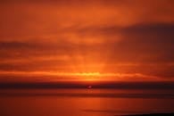 平静的海面上，迷人的橙红色日落捕捉到了大自然的美丽