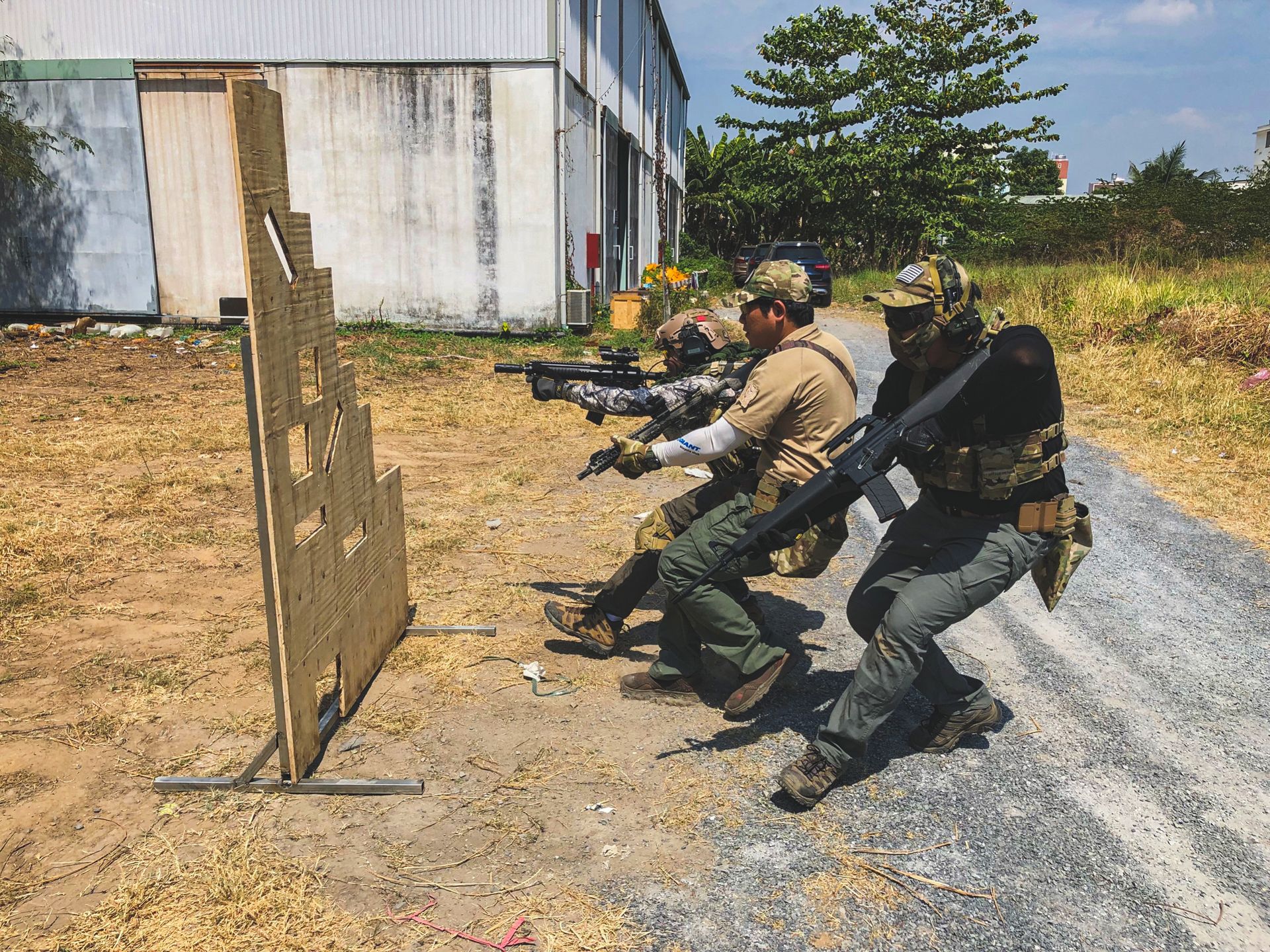 Group of soldiers practicing tactical maneuvers with rifles outdoors.