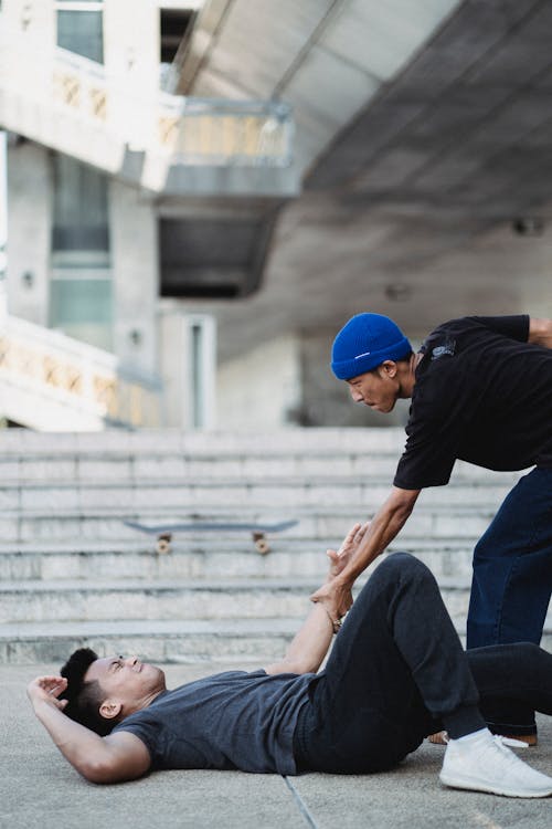 Free Asian man helping friend while meeting on street Stock Photo