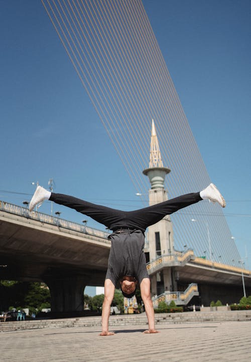Free Full body of determined male athlete doing handstand exercise on street while dancing break Stock Photo