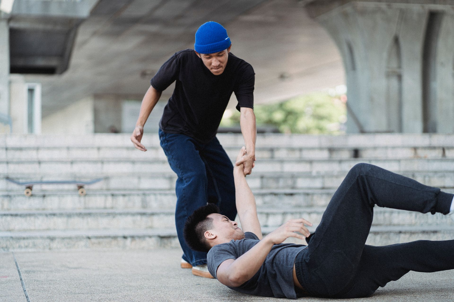 Young Asian man helping friend on pavement