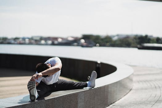 Full body of faceless male athlete in sportswear stretching body while training on city street