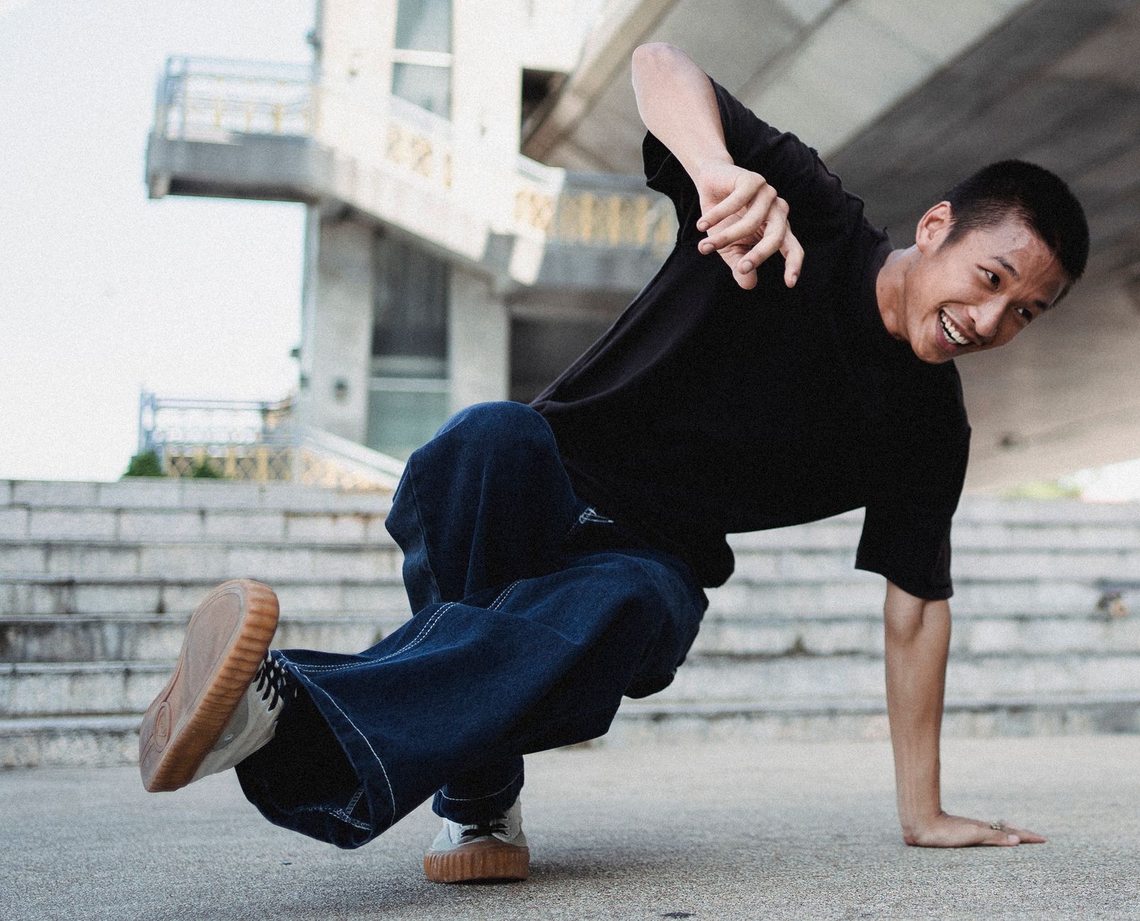 Full body of ethnic male in casual clothes smiling while dancing break on city street