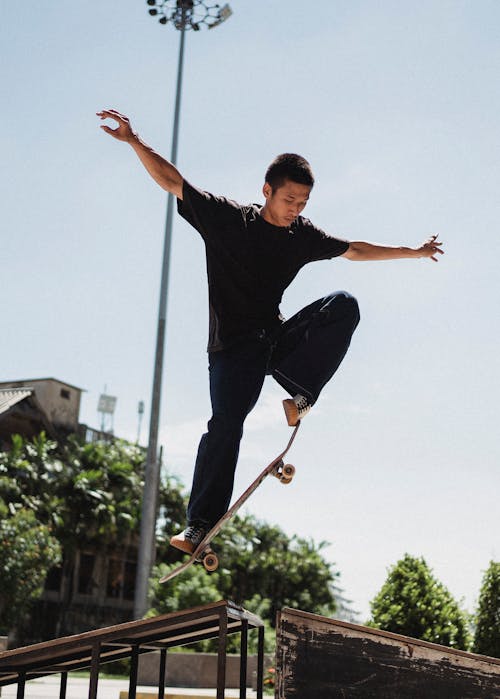 Sportive Asian man doing trick on skateboard