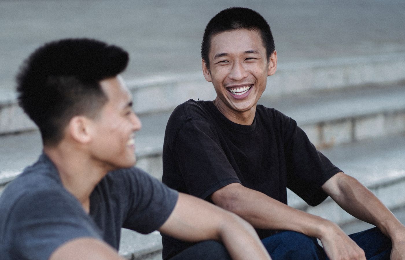 Asian men enjoying a lighthearted conversation on steps, capturing friendship and leisure.