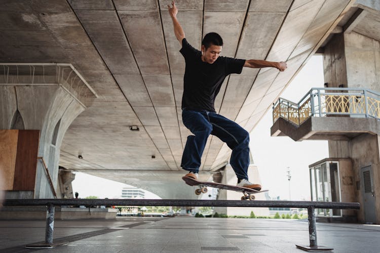 Active Asian Man Performing Trick On Railing