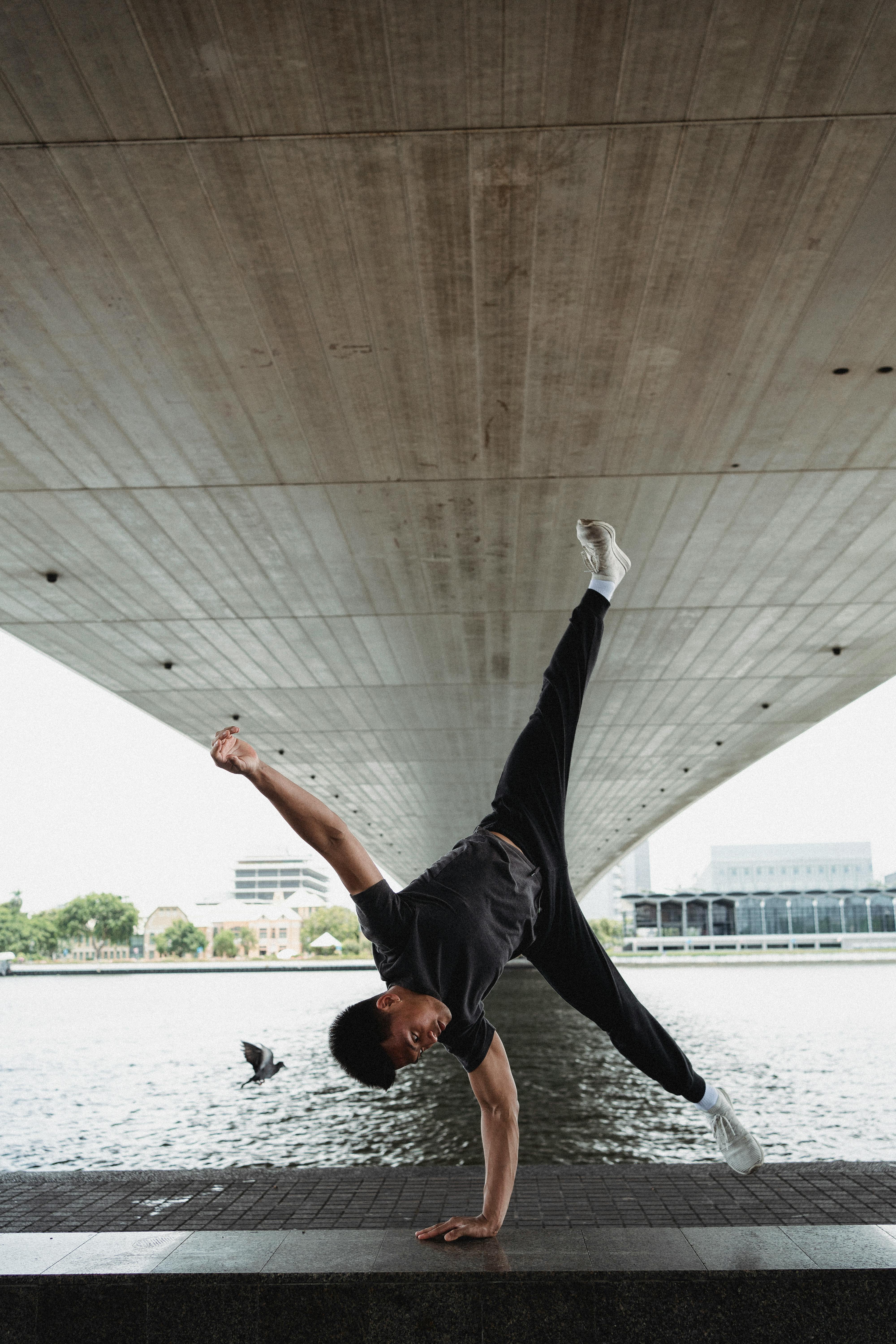 Flexible man doing handstand on seafront · Free Stock Photo