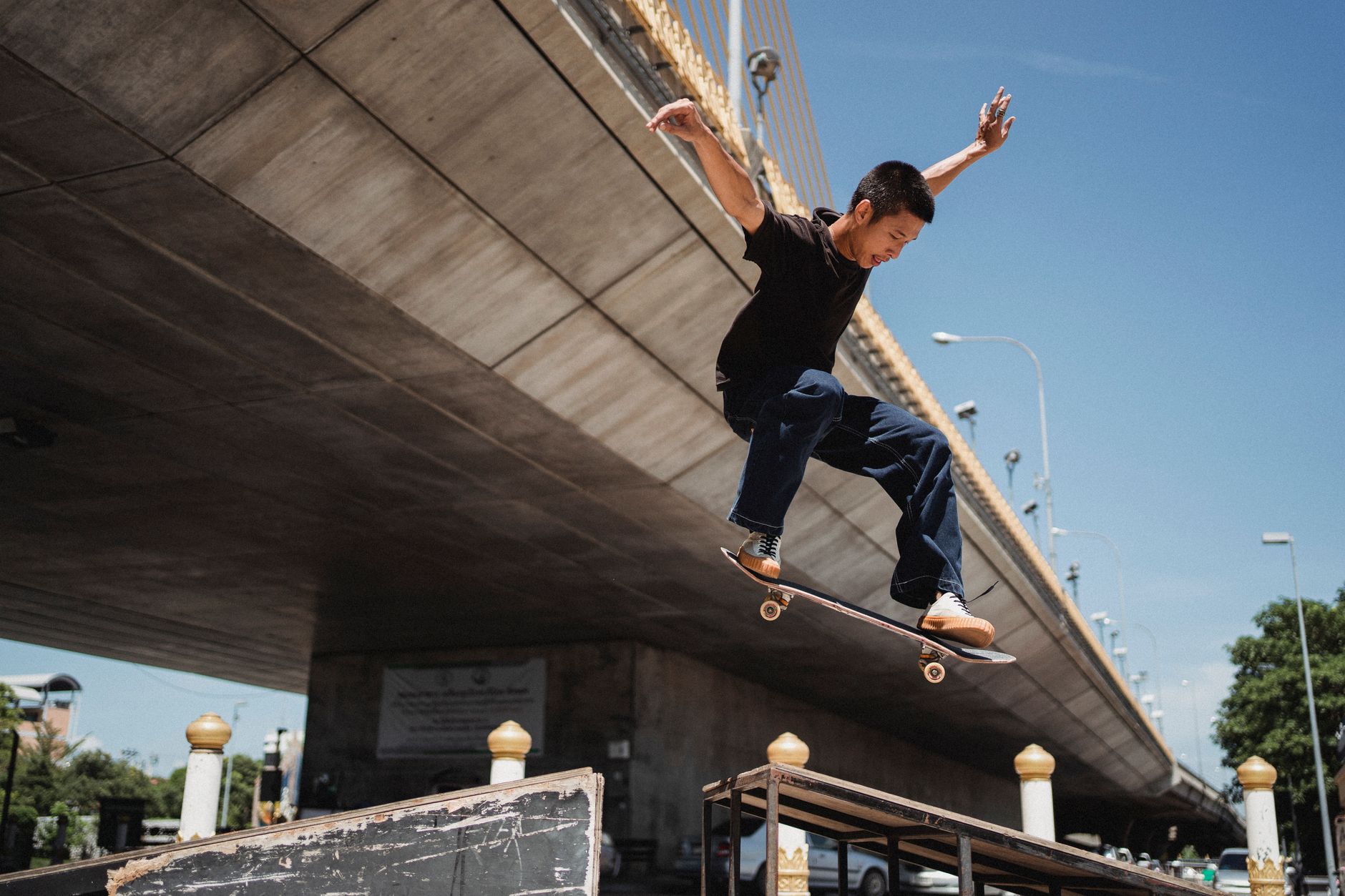 โทรศัพท์มือถือเปิดหน้าบล็อก Cockfight Skateboards บนโต๊ะไม้ข้างรองเท้าสเกตและนิตยสารพังก์