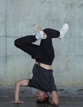 一名神情严肃的年轻男运动员身穿运动服，在石墙边一边跳舞一边锻炼