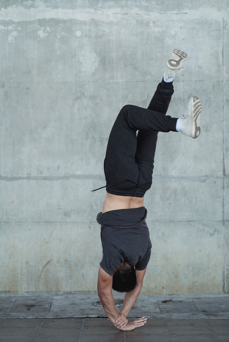 Flexible Man Doing Handstand Near Wall