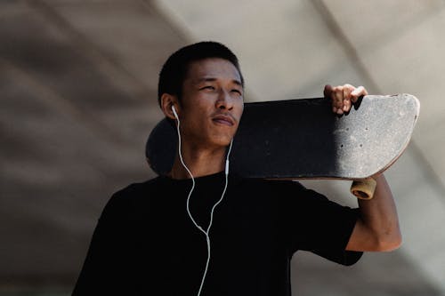 Free Young Asian man with earphones and skateboard Stock Photo