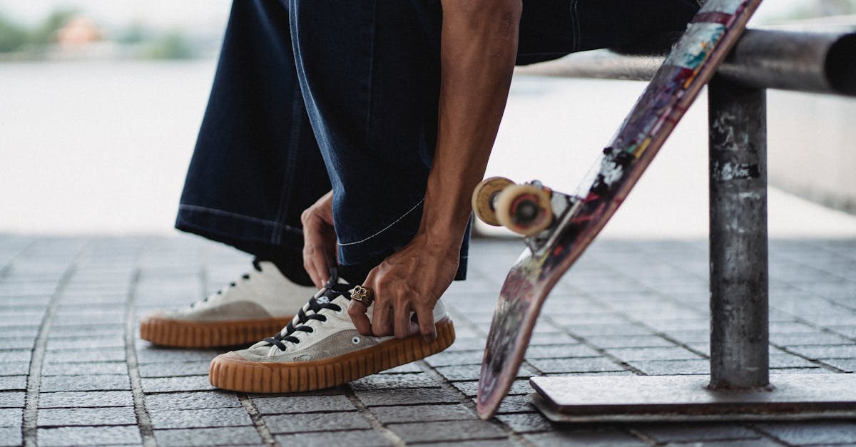 Man in denim touching sneakers near skateboard on concrete tile · Free ...