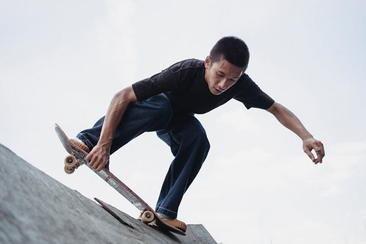 Slim Young Asian Man Skateboarding On Rough Ramp