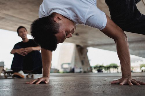 Free Young Asian male doing stunts under concrete roof on blurred background of park Stock Photo