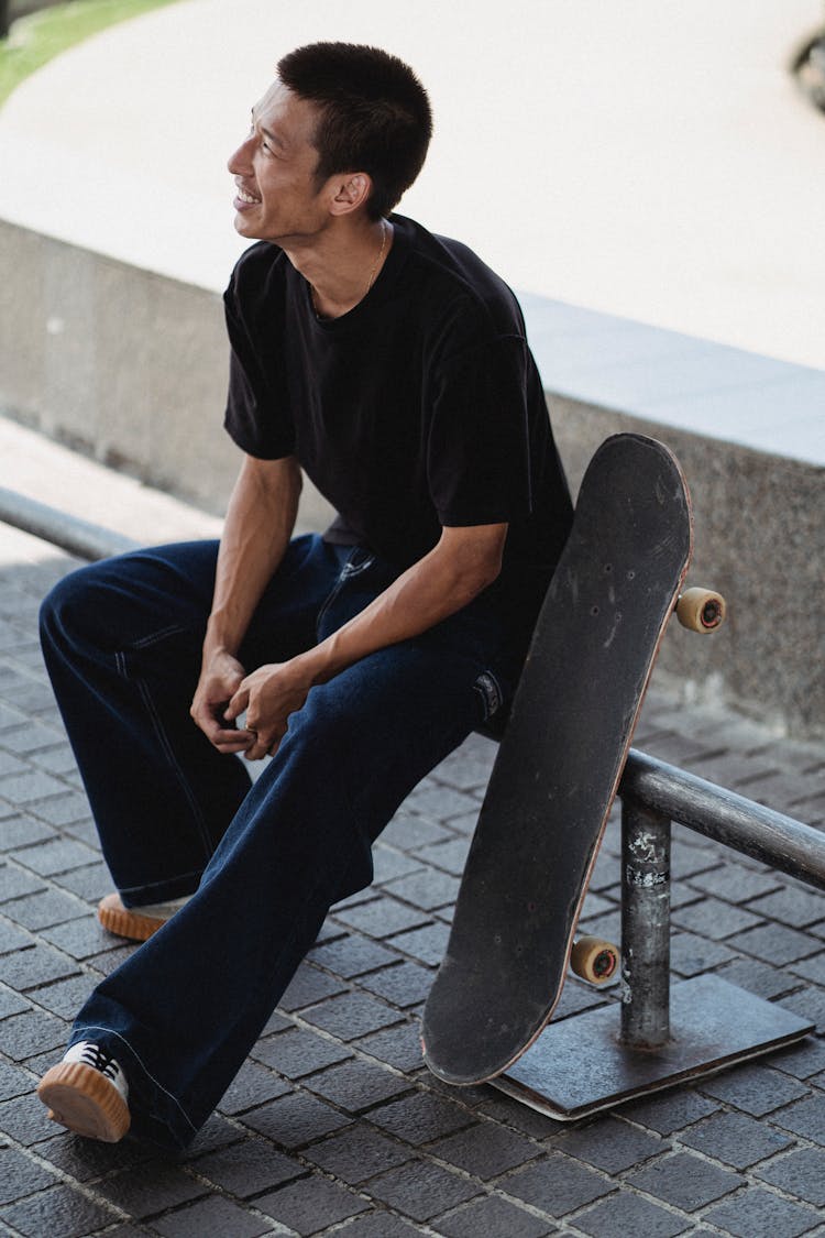 Young Asian Man With Skateboard Smiling