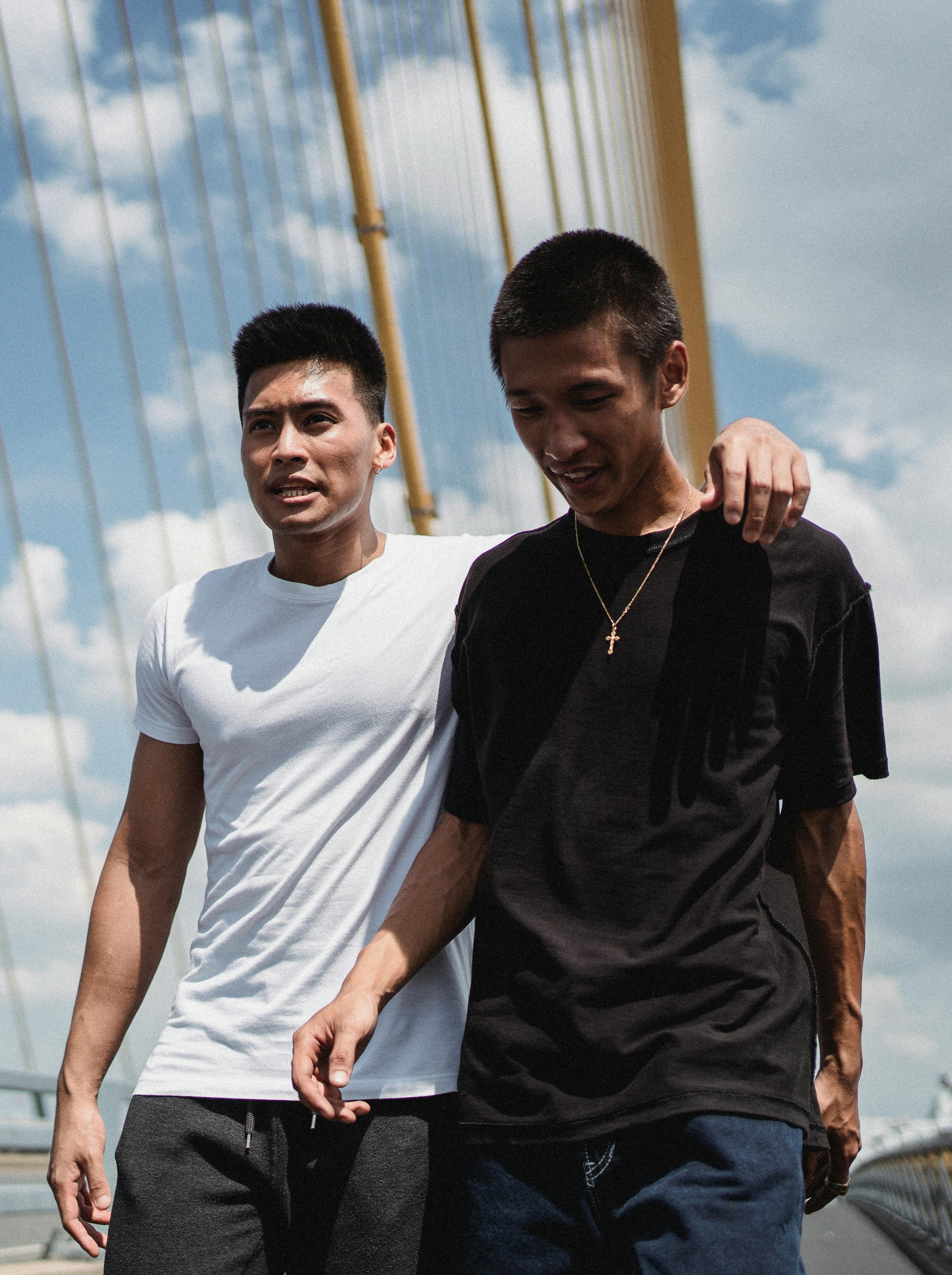 asian friends hugging on bridge on sunny day