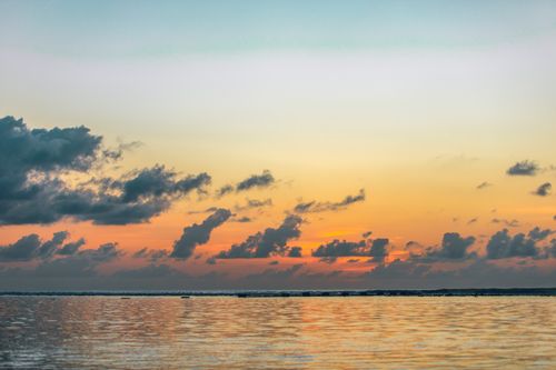 Free Picturesque scenery of bright orange sun setting over rippling calm sea in early evening Stock Photo