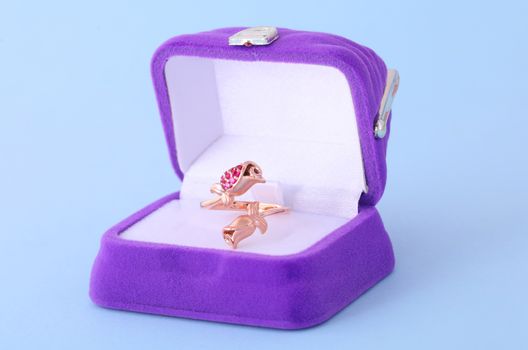 A close-up of an elegant rose gold bird-shaped ring in a luxurious purple ring box.