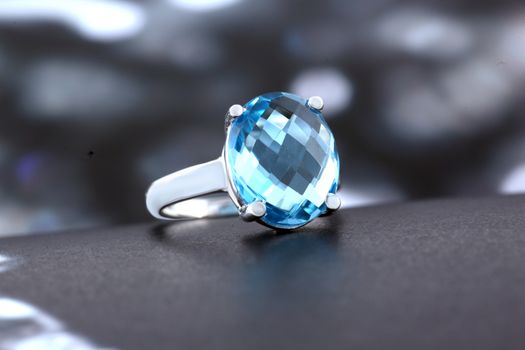 Detailed close-up of a luxurious silver ring with a sparkling blue gemstone, perfect for a jewelry showcase.