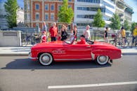 A Man Riding a Red Convertible Car