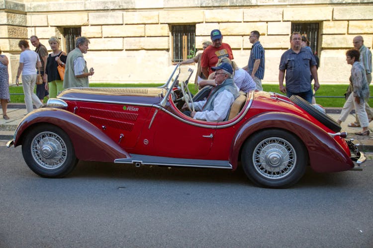 An Elderly Man Riding A Vintage Car