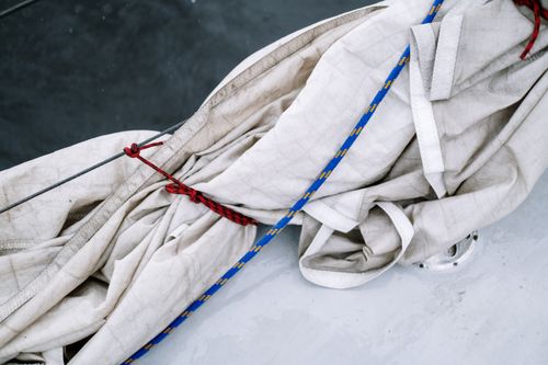 Free Detailed view of a sail tied with red and blue ropes on a boat, showcasing nautical details. Stock Photo