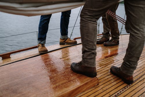 Persoon In Blue Denim Jeans En Bruin Lederen Laarzen Staande Op Bruin Houten Dok