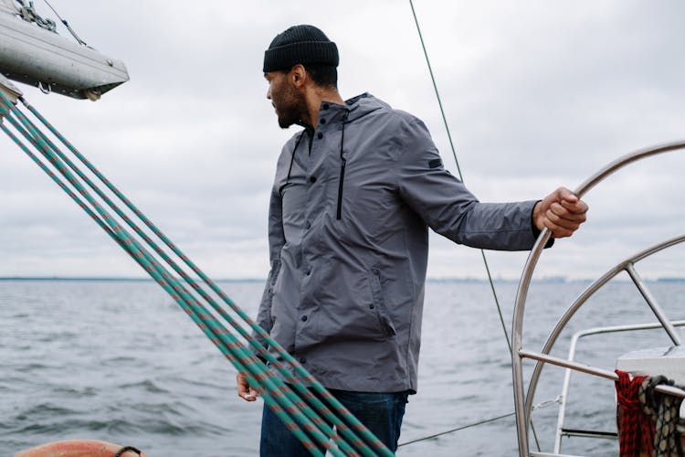 A Man Wearing A Jacket While Standing On The Boat 