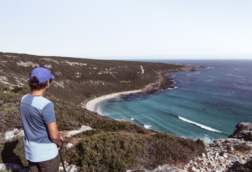 Free Man overlooking a beautiful coastal view with cliffs and the ocean in daylight. Stock Photo
