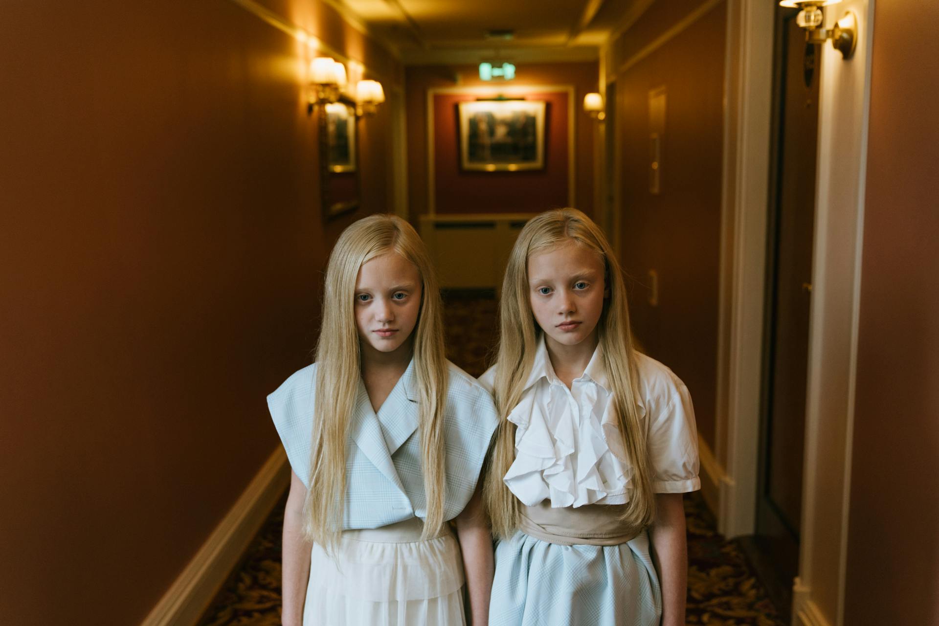 Twin Girls Standing in a Hotel Hallway