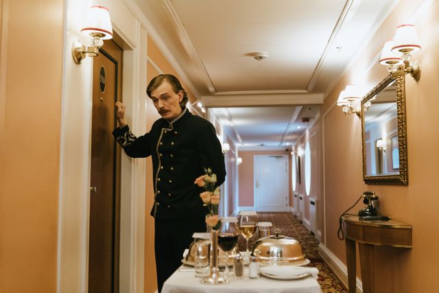 A hotel staff member in uniform serves room service with a trolley in a luxurious hallway. Related image for Hotel Operations: Why Independent Hotels Are Investing Now.