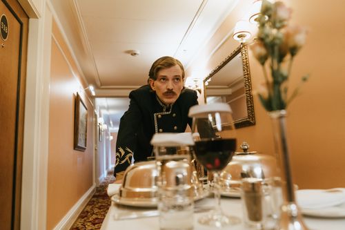 Free A hotel staff member in uniform delivering room service in an elegant hallway. Stock Photo