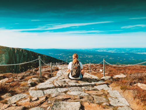 Blonde Woman Sitting on Rocky Footpath in Mountains