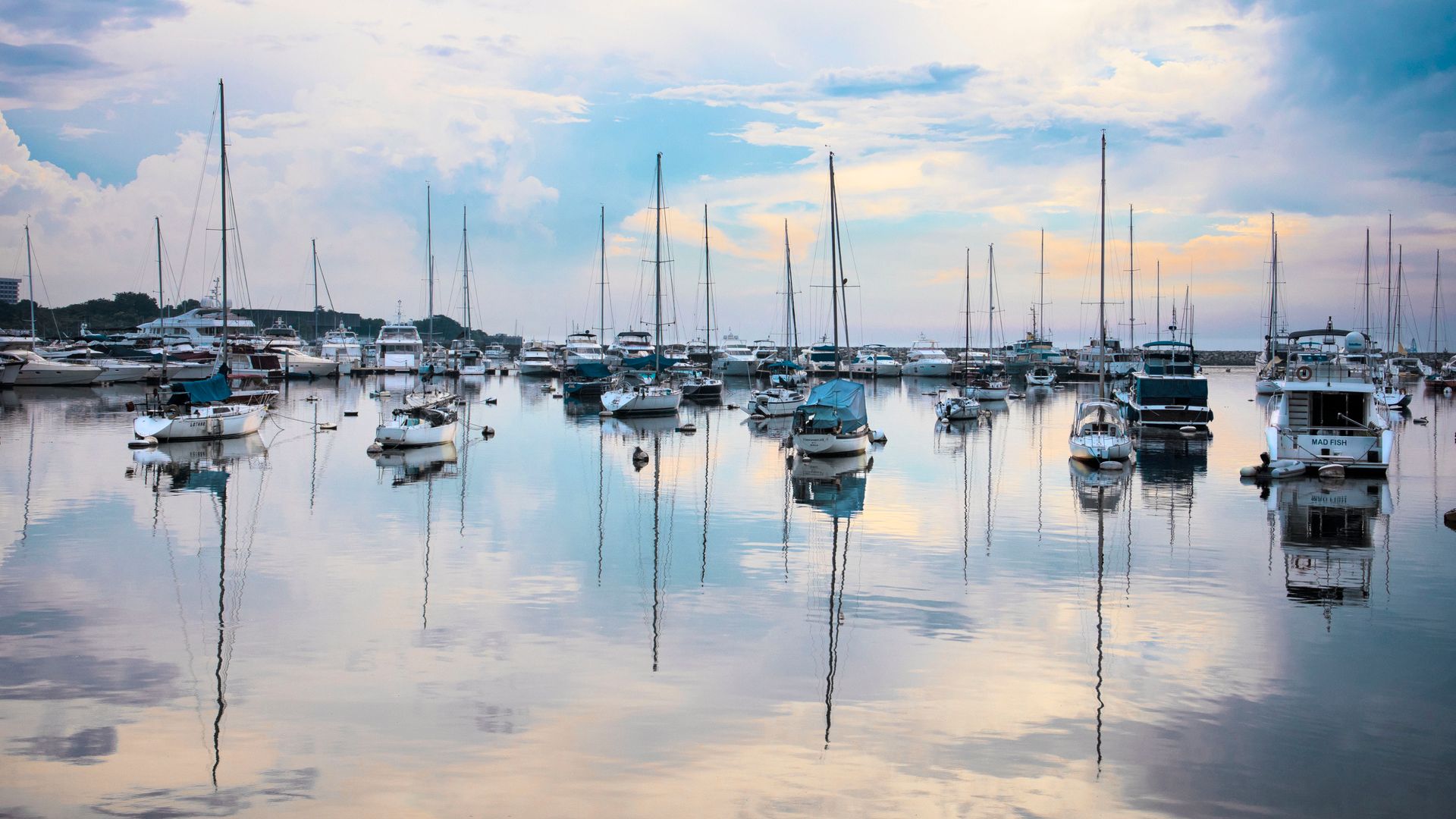 Serene view of boats docked in a calm harbor with beautiful sunset reflections on the water.