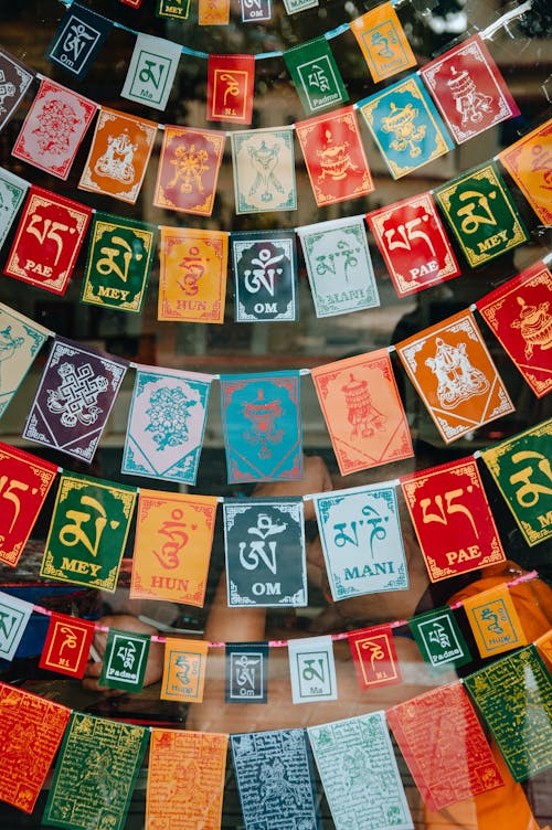 Various colorful religious signboards with inscriptions and letters in Sanskrit hanging in glass showcase