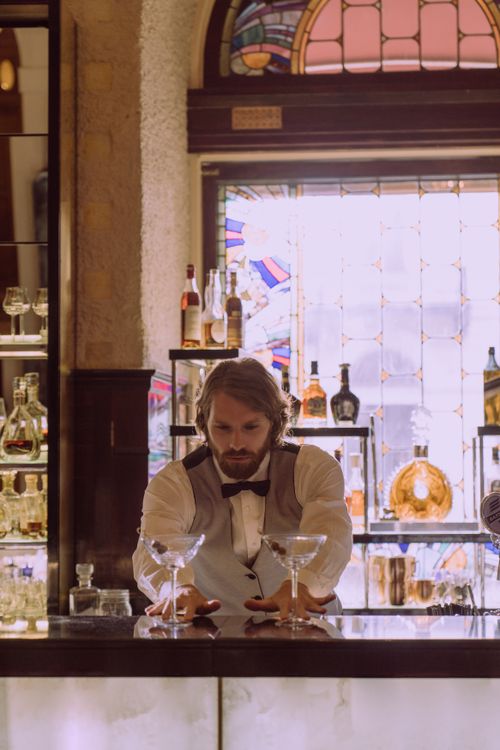 Free A sophisticated scene of a bartender organizing glassware in a vintage-themed bar setting. Stock Photo