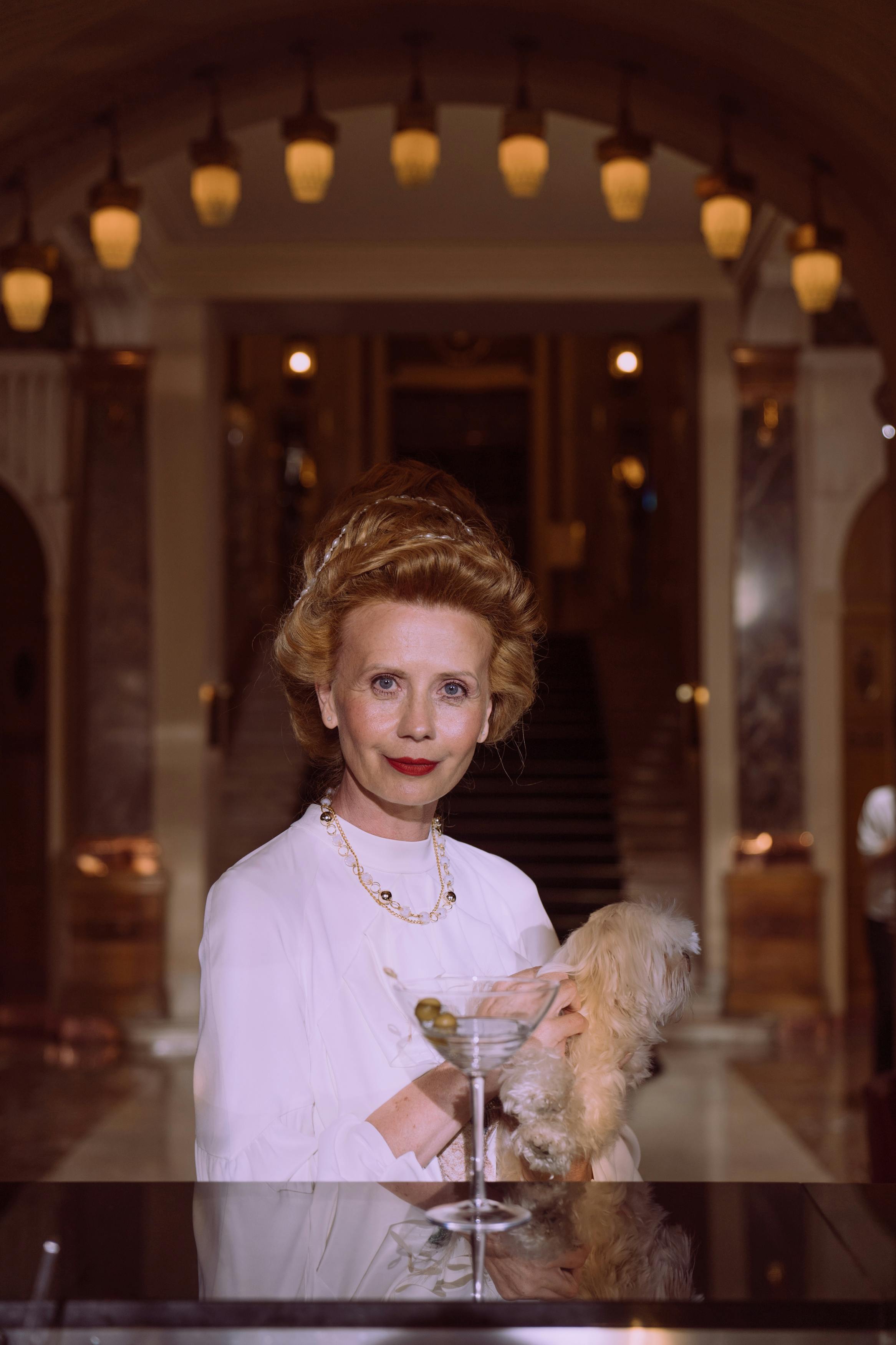 一位精致的女士，在马耳他风格的奢华内饰中，手持马提尼酒