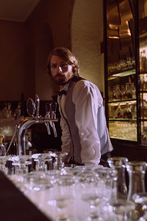 Free Sophisticated bartender in a stylish vest, preparing drinks in a dimly lit bar. Stock Photo