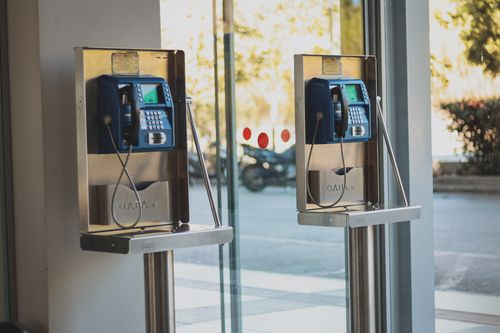 Free Two blue modern phone booths by a glass doorway in a city setting, showcasing urban technology. Stock Photo