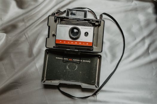 Close-up of a vintage Polaroid Land Camera on gray fabric, showcasing retro photography equipment.