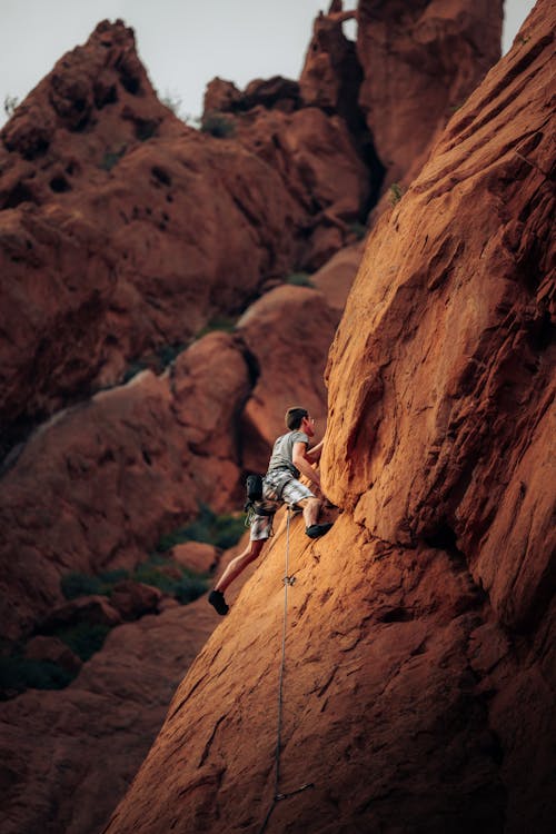 A Man Climbing Brown Rock Mountain