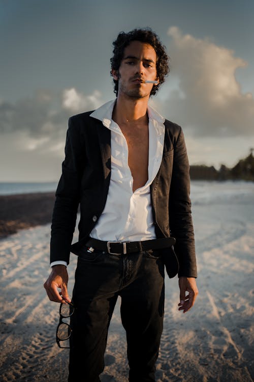 Man with Open Shirt and Smoking Standing on Beach