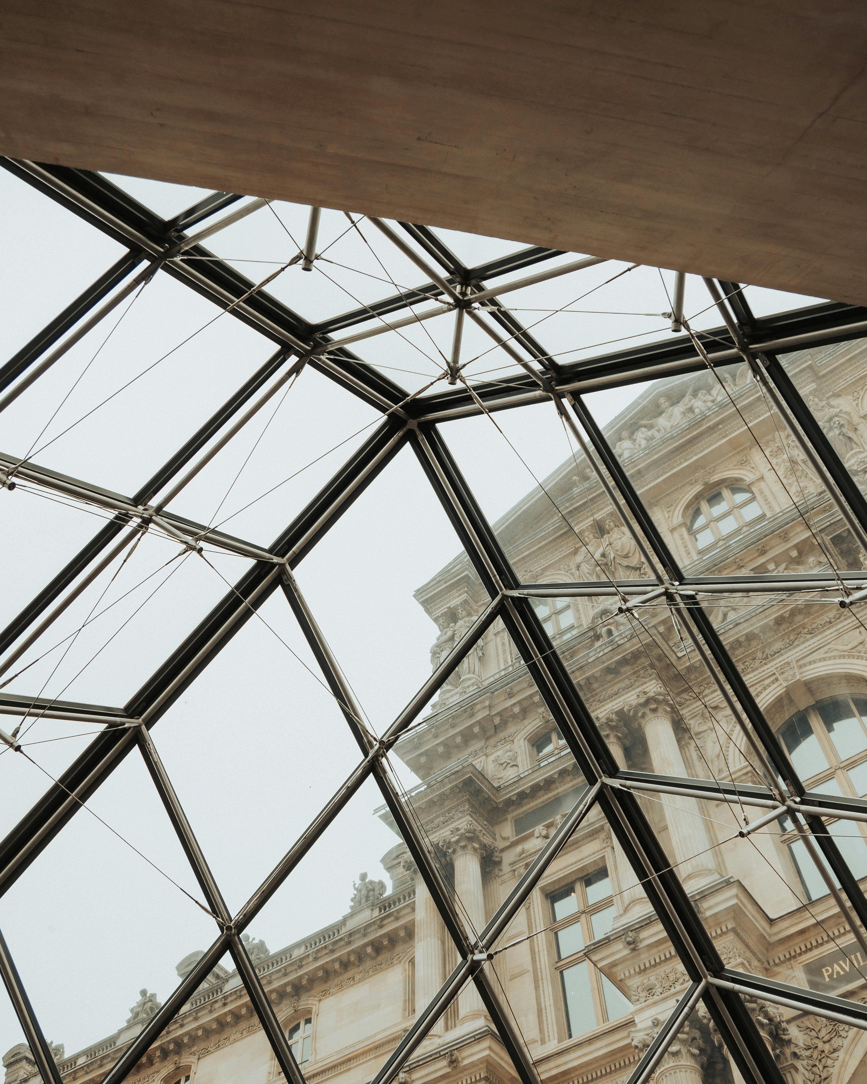 A striking perspective of the Louvre Museum facade through the iconic glass pyramid in Paris.