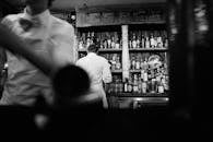 一张黑白照片捕捉了调酒师在复古酒吧工作的场景