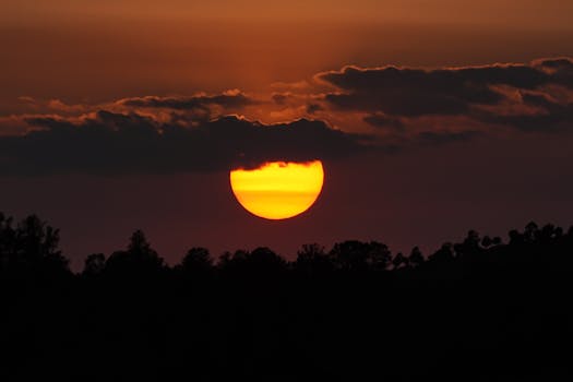 Beautiful sunset with dramatic clouds casting silhouettes over trees.