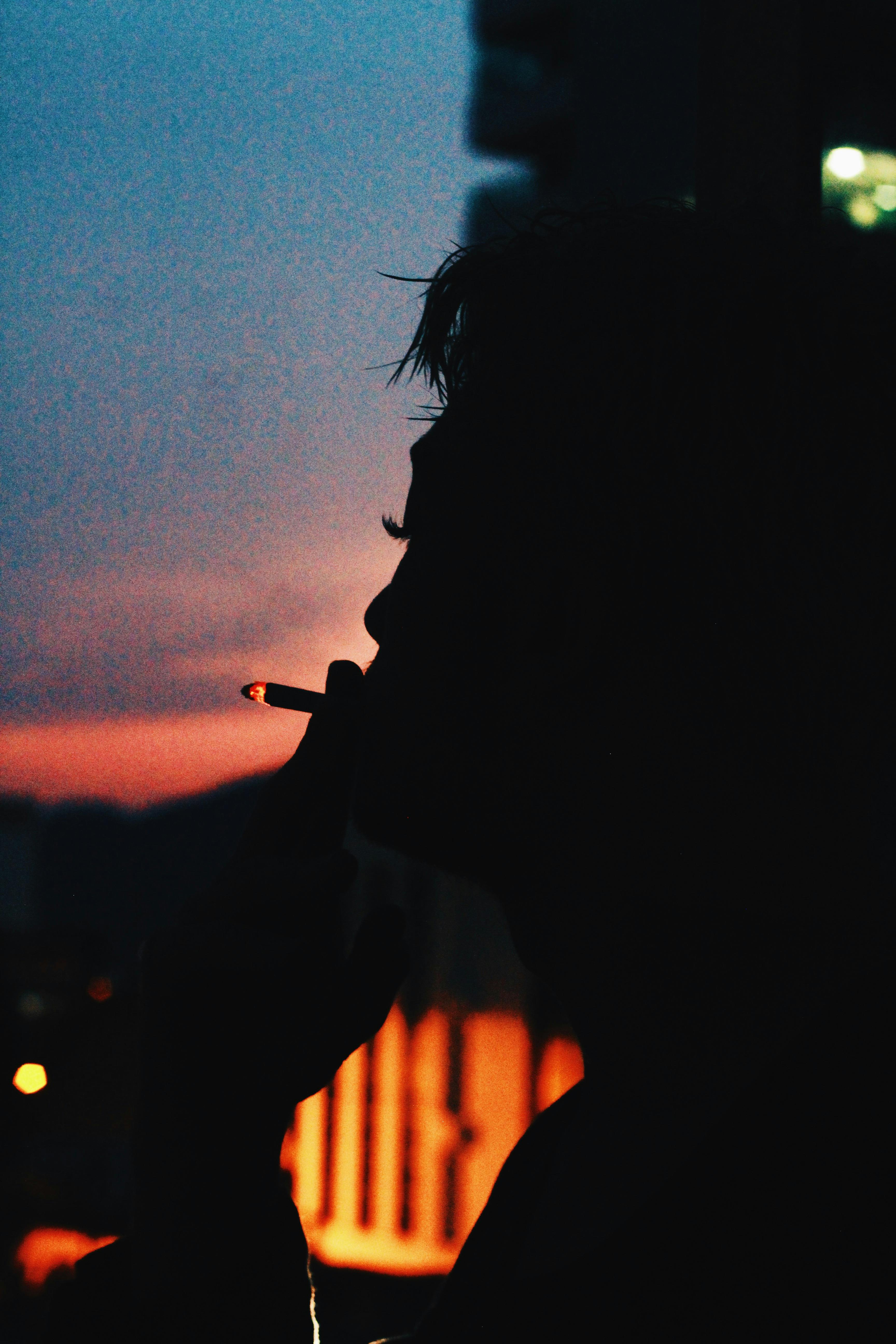 calm person with burning cigarette smoking in dark evening