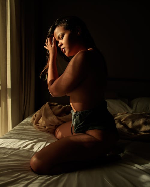 Free Topless Woman Kneeling on a Bed Stock Photo